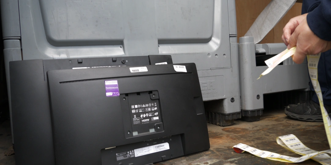 Retired monitor with asset labels attached during the IT asset disposal and tracking process.
