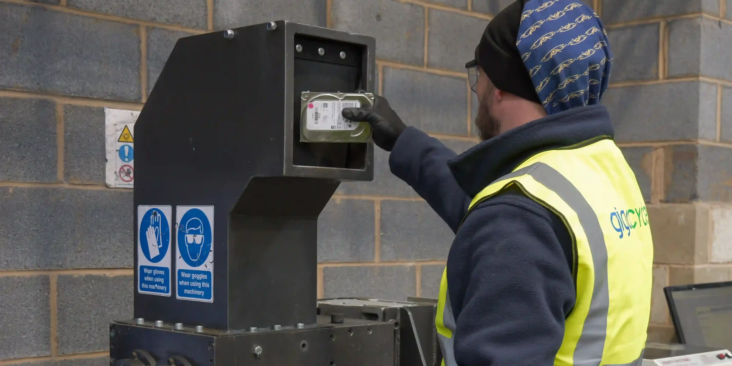 Worker operating equipment to physically destroy hard drives